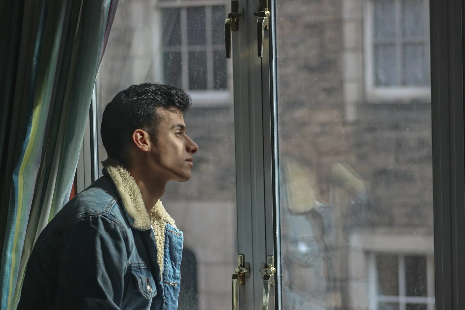 A person looking out of a window, thinking something through