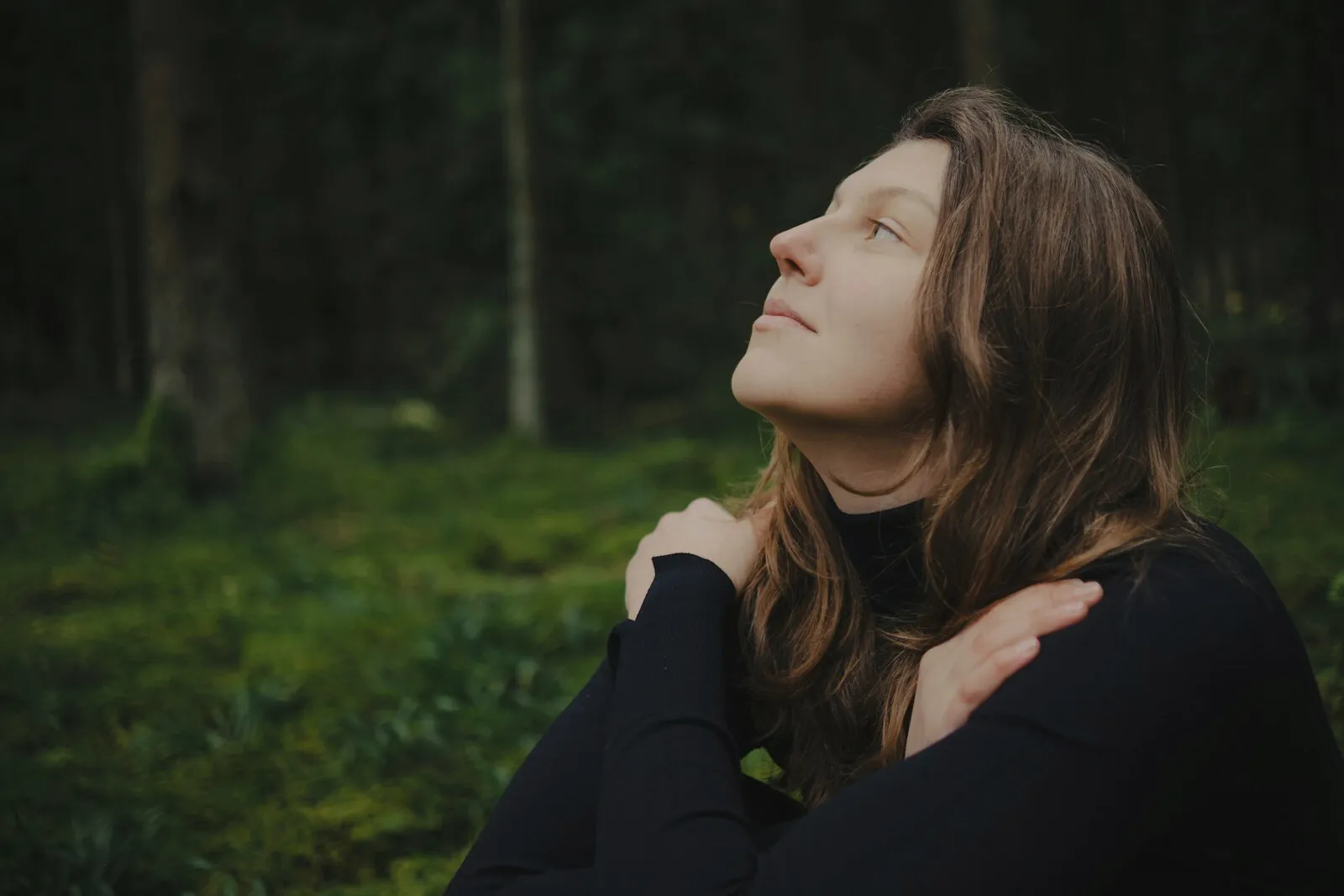 A person outdoors with their eyes closed, at ease