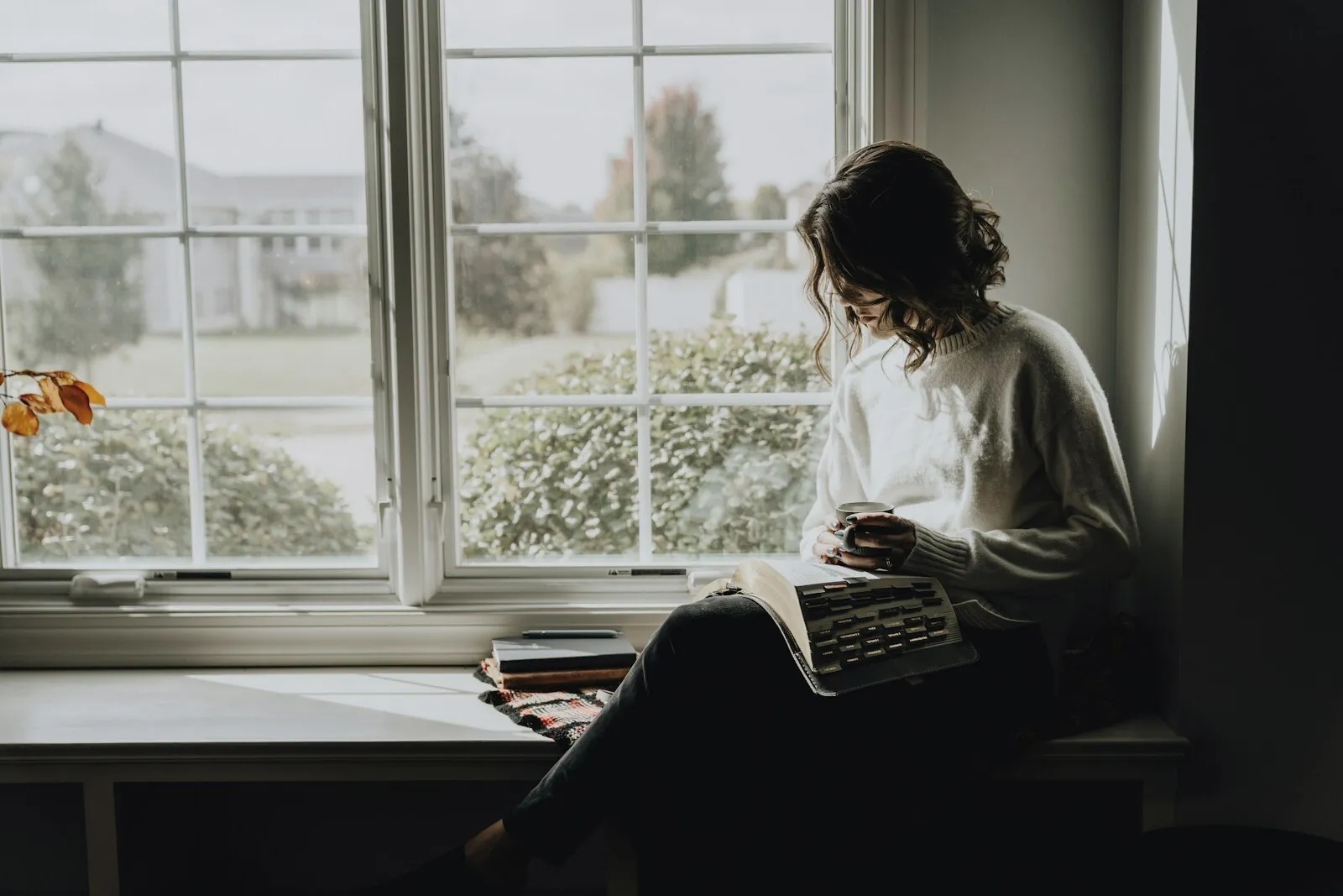 A person sitting alone at a window, thinking