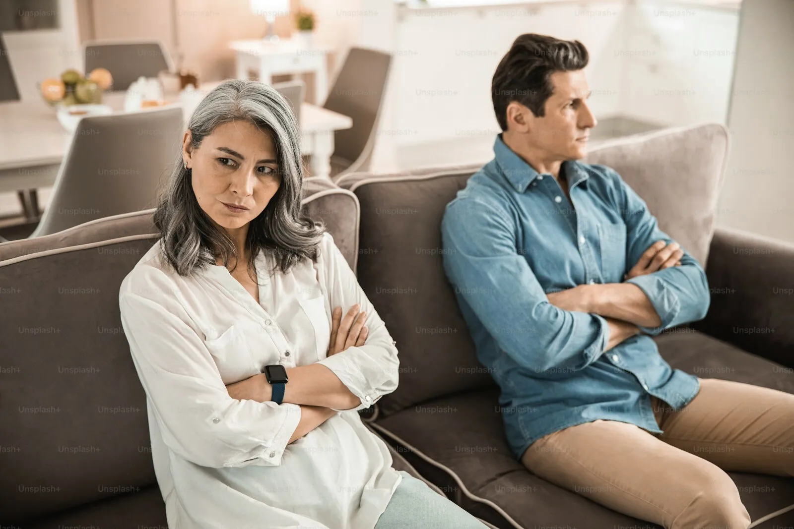 A couple sitting apart on a sofa, turned away from each other