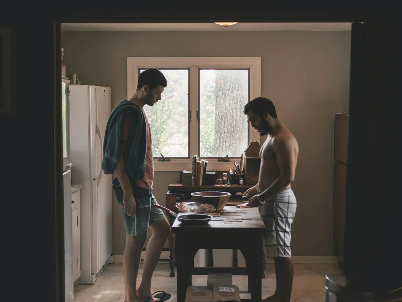 Two men in a quiet kitchen, apart and not speaking