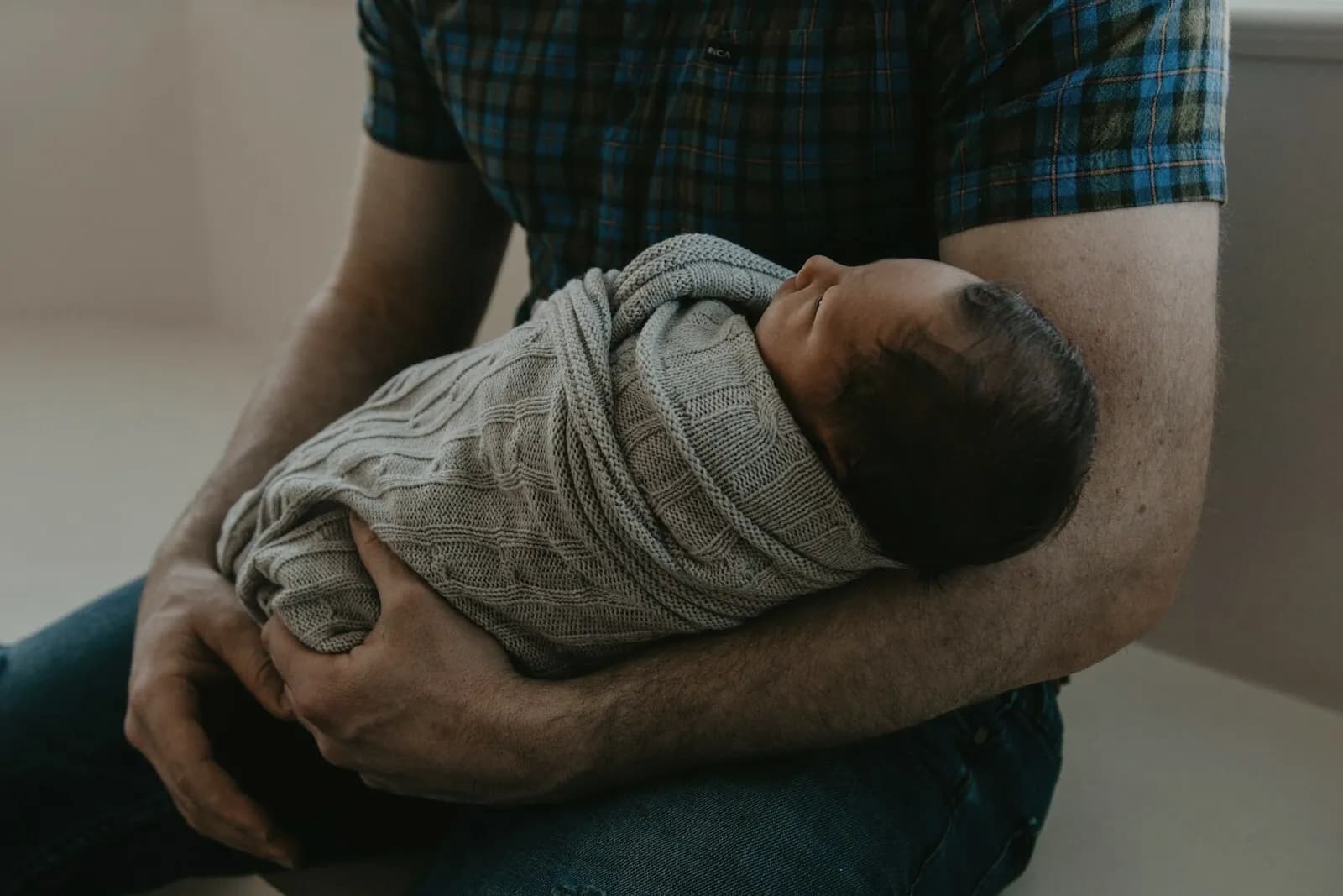 A father cradling a swaddled newborn