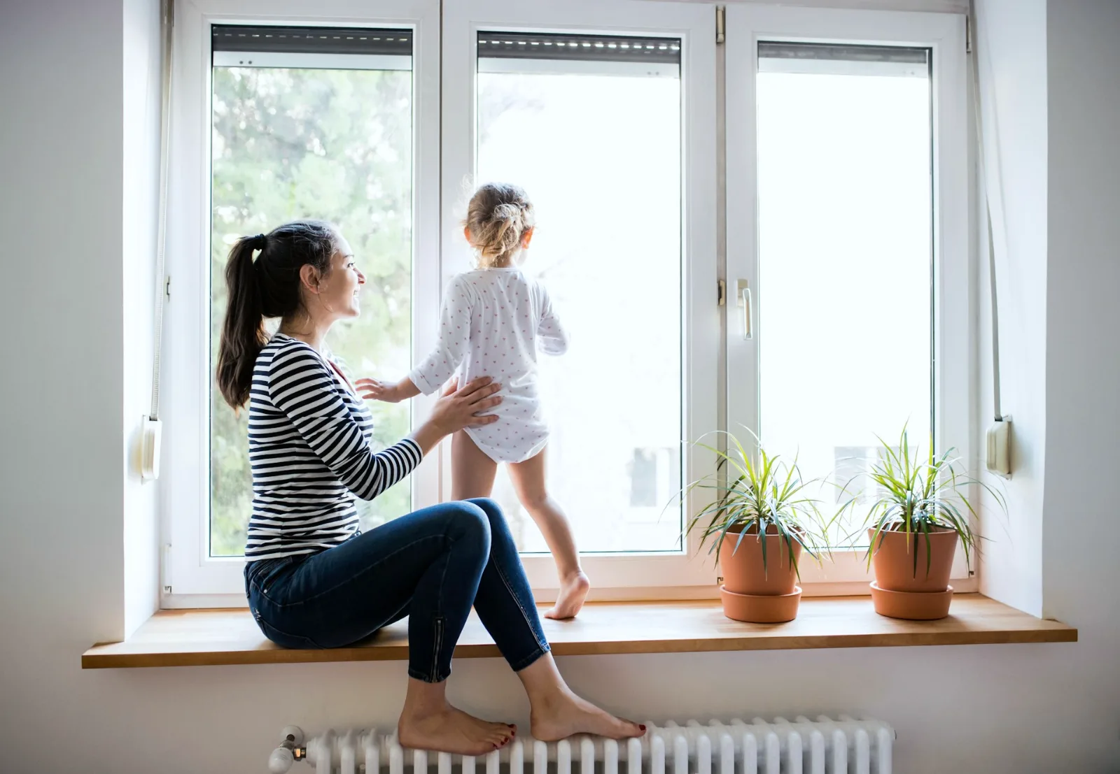 A parent sitting with a young child at a bright window