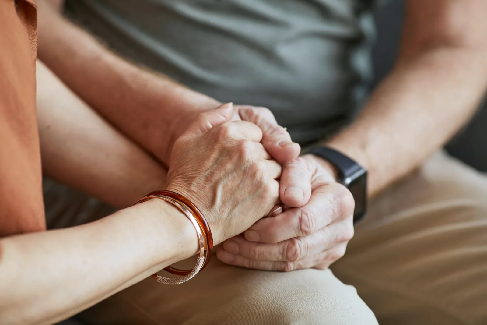 Two people sitting together with hands clasped in their laps
