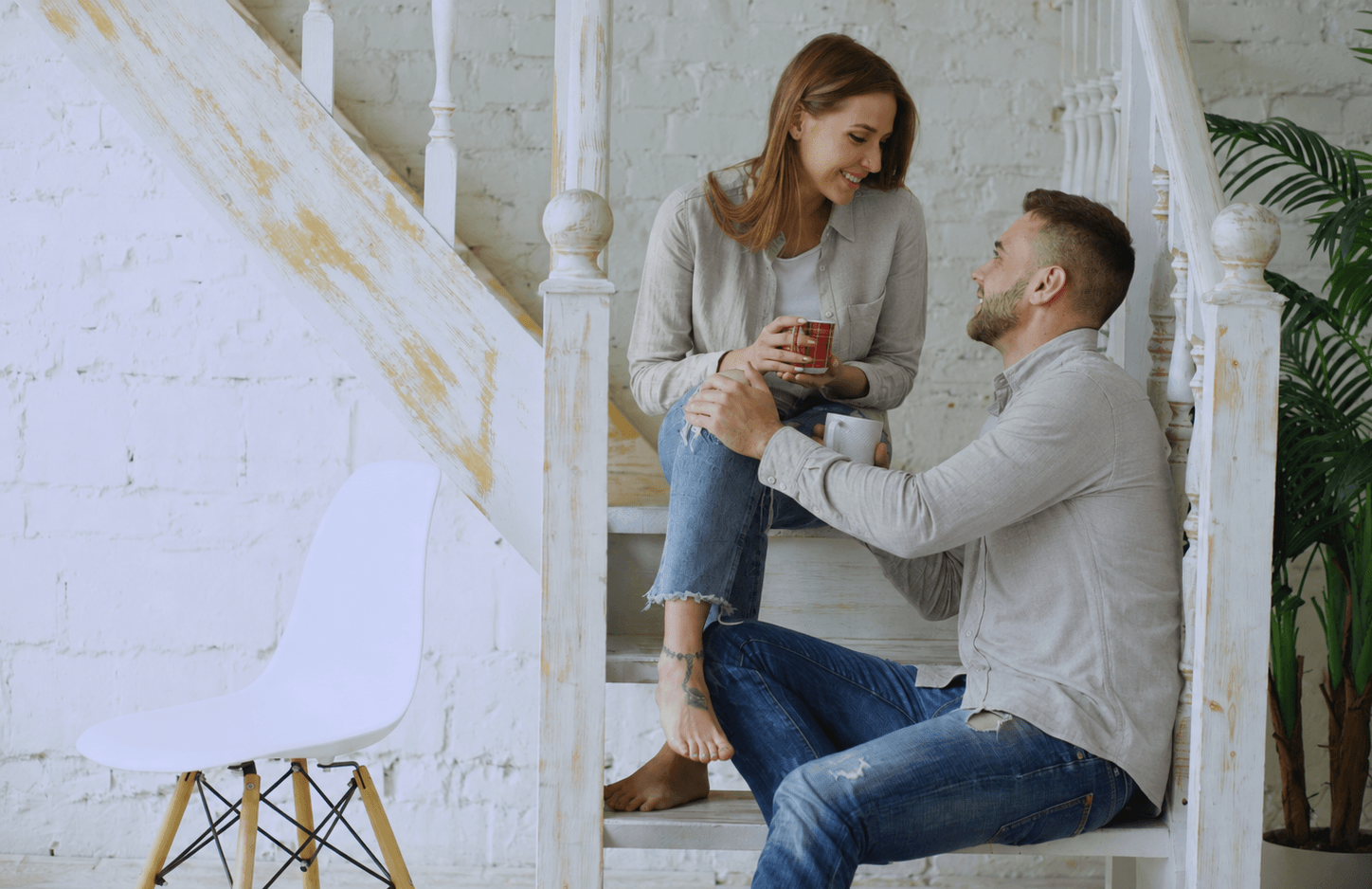 A couple sitting on the stairs drinking coffee