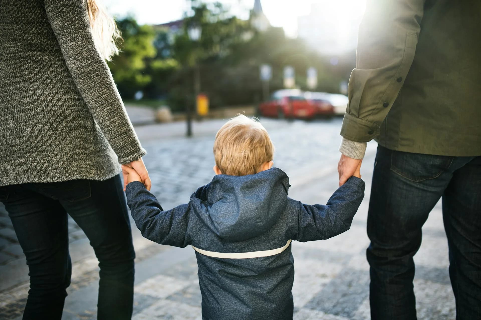 A child holding both parents' hands while they walk